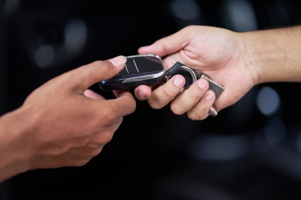 A car key being passed between two hands.