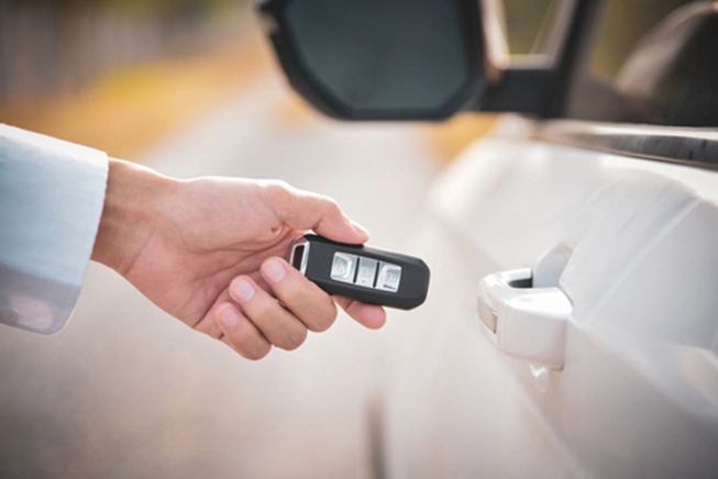 A hand holding a key next to a car door