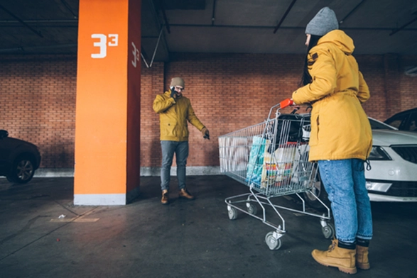 A couple with a shopping trolley standing in front of an empty parking space