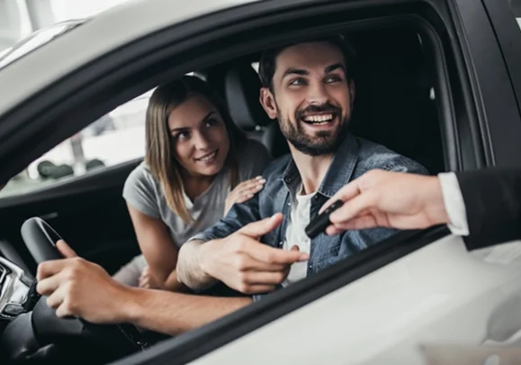 A couple sitting in a car, receiving a new pair of keys