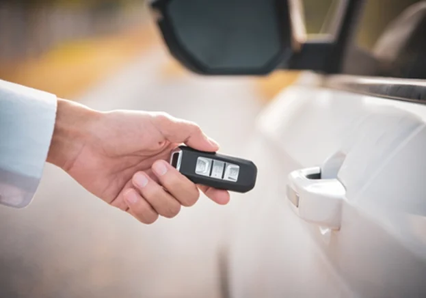 A hand holding a key next to a car door