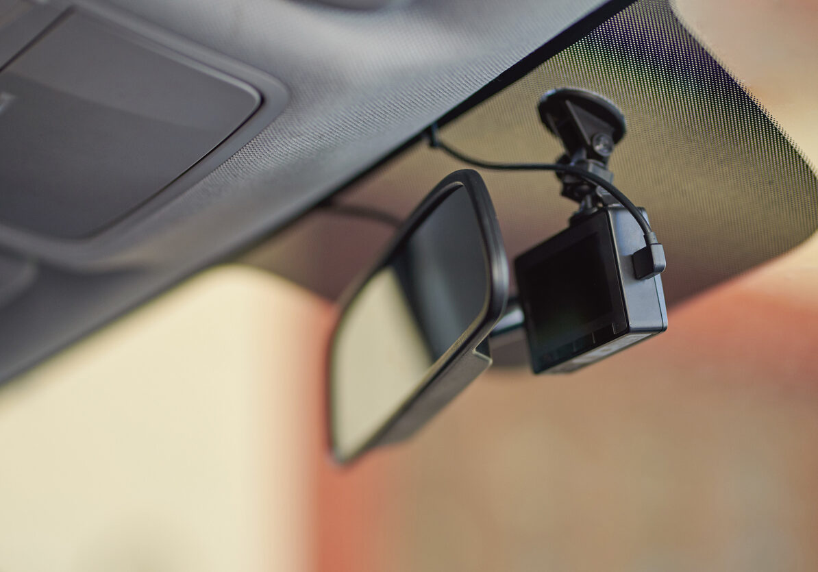 Small black car camera on windshield behind mirror