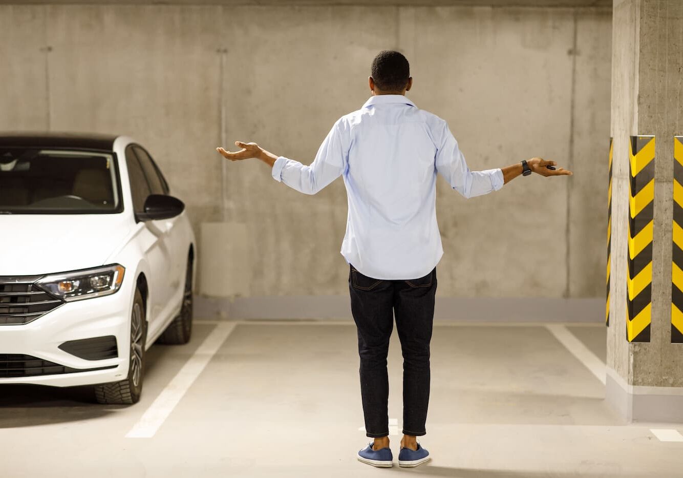 A man standing in a parking lot with his arms outstretched