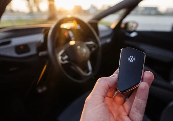 Hand holding a VW key in front of VW